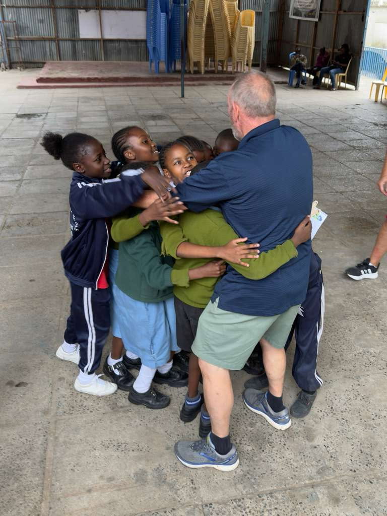 Bill Smith hugged by five African schoolchildren
